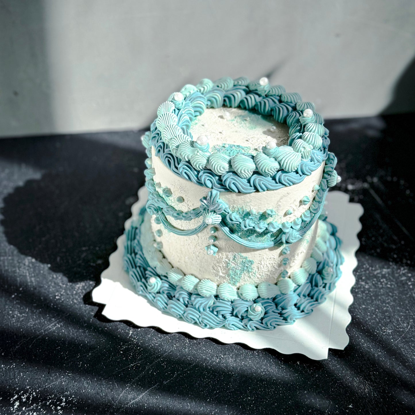 Vintage cake from Kaki Desserts with layered frosting and decorative toppings, showcasing a classic dessert presentation.