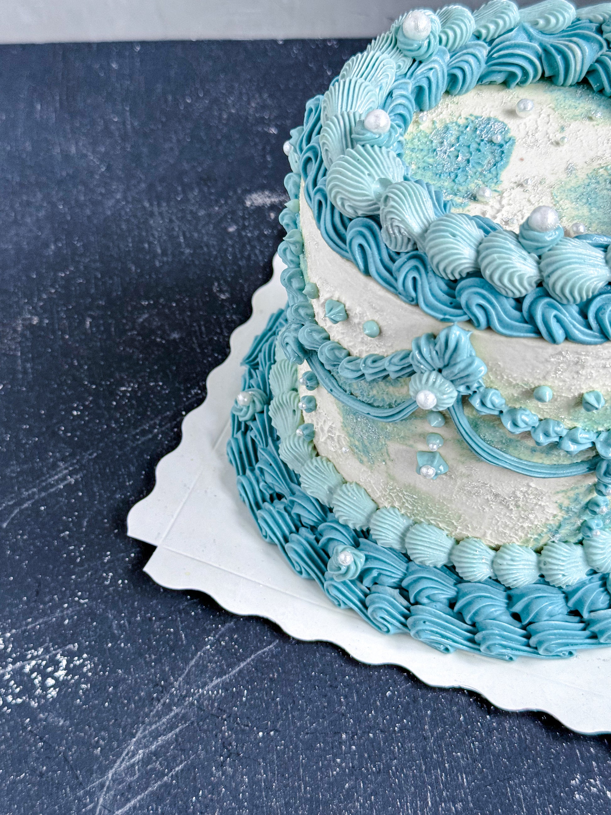 Vintage cake from Kaki Desserts with layered frosting and decorative toppings on a white serving plate.