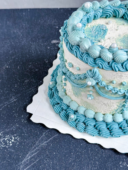 Vintage cake from Kaki Desserts with layered frosting and decorative toppings on a white serving plate.