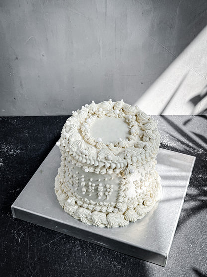 Decorative bespoke cake from Kaki Desserts featuring colorful icing and intricate design on a white background.