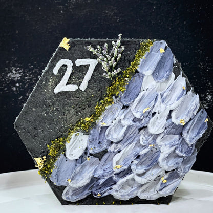 Decorative bespoke cake from Kaki Desserts with intricate icing designs and colorful floral accents, displayed on a white cake stand.