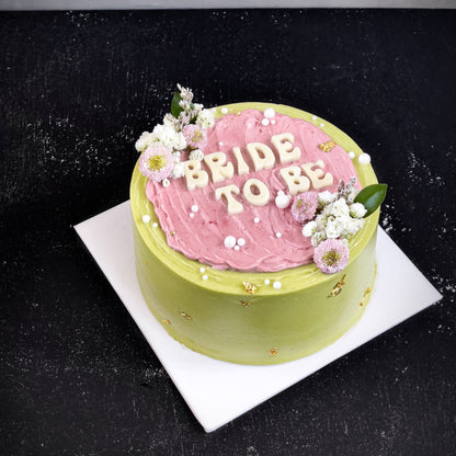 Decorative bespoke cake from Kaki Desserts featuring intricate icing designs and colorful floral accents.