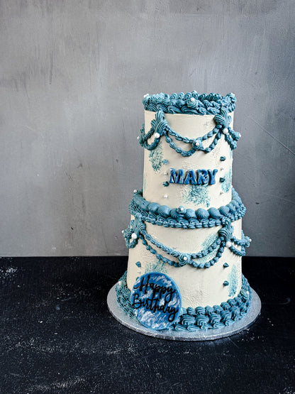 Vintage cake from Kaki Desserts with elegant frosting and decorative toppings, displayed on a plate.