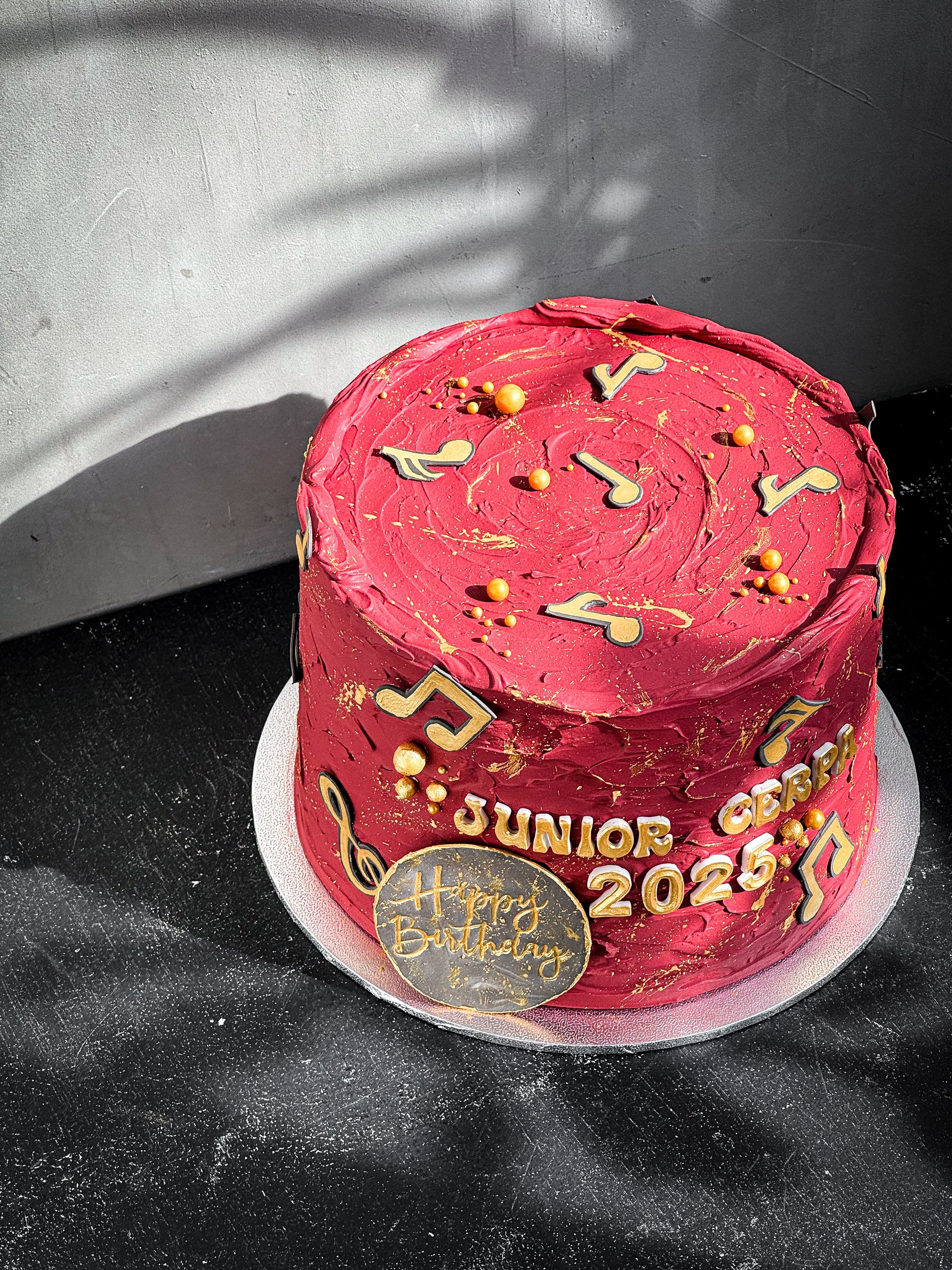 Colorful bespoke cake from Kaki Desserts with intricate floral decorations and layered frosting on a white cake stand.