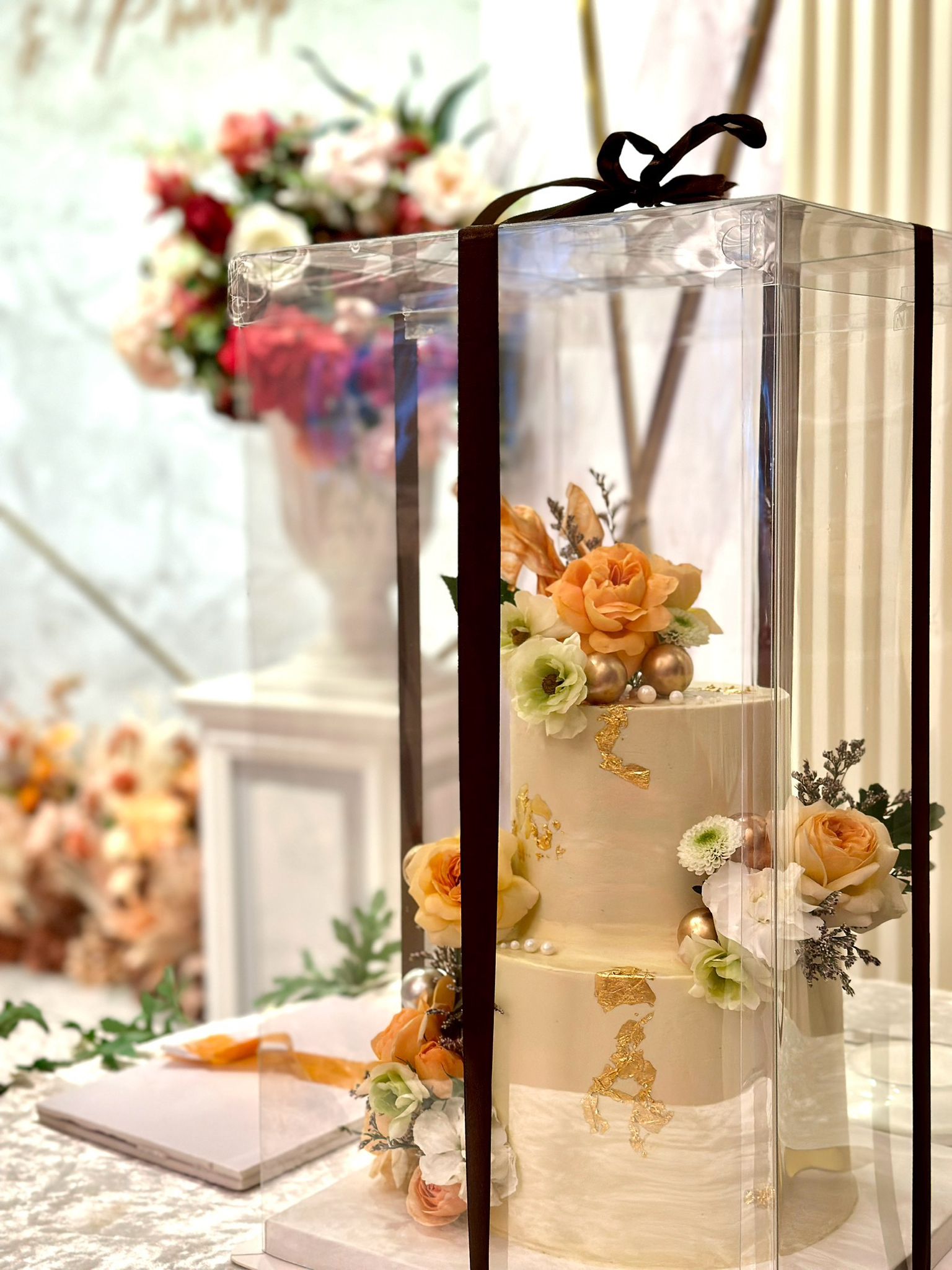 Multiple tier cakes from Kaki Desserts displayed on a table, showcasing elegant layered desserts with decorative frosting and toppings.