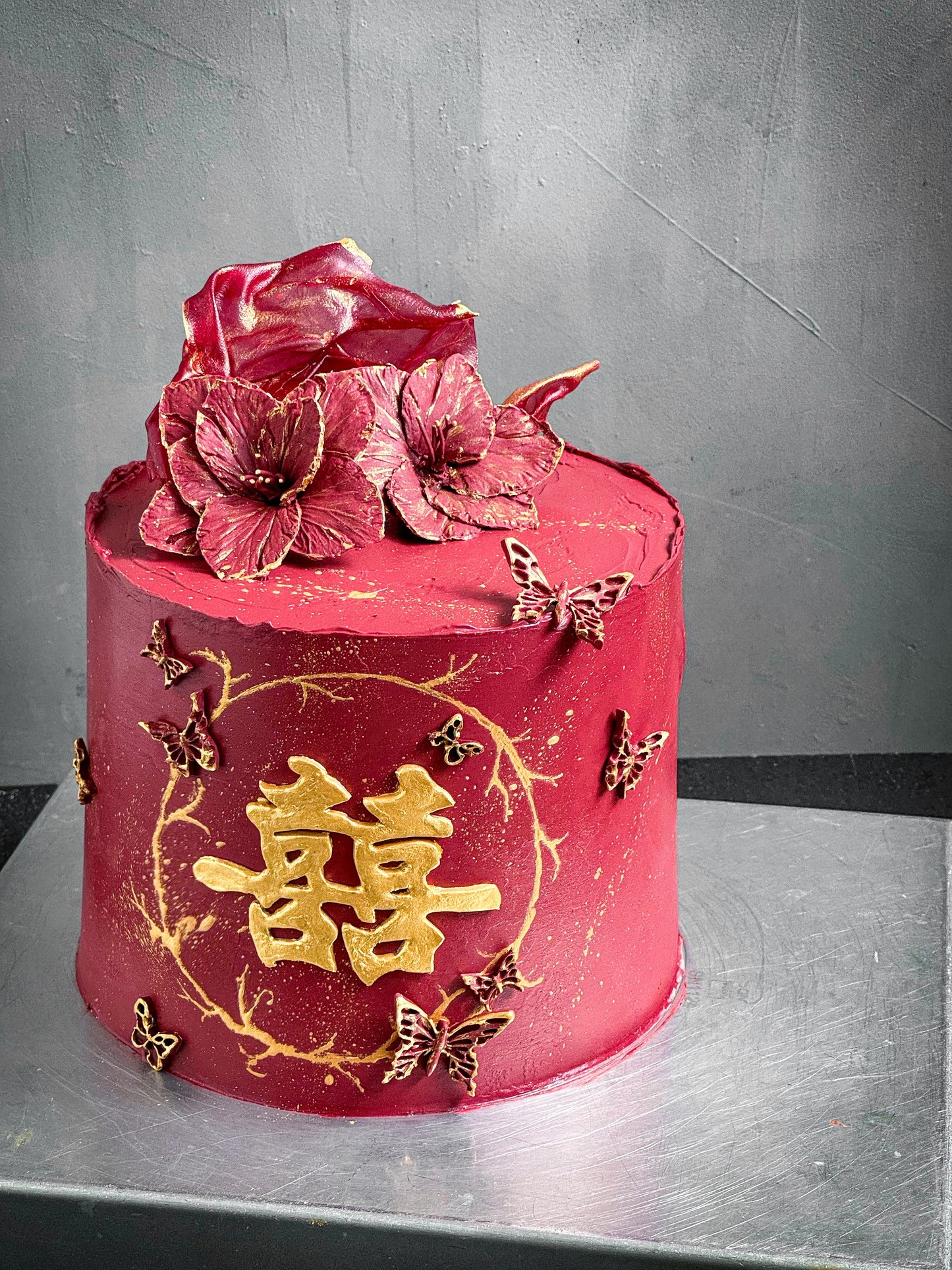 Decorative bespoke cake from Kaki Desserts with intricate floral and swirl icing details on a white cake stand.