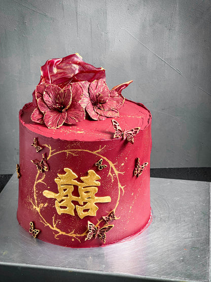 Decorative bespoke cake from Kaki Desserts with intricate floral and swirl icing details on a white cake stand.