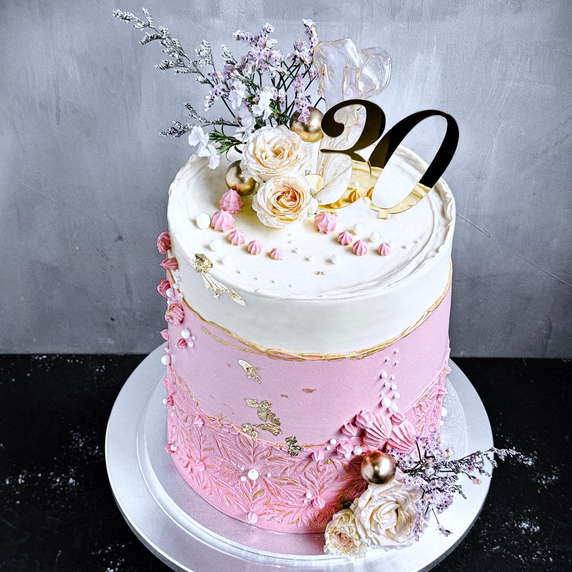 Decorative bespoke cake from Kaki Desserts featuring intricate piping and colorful floral details on smooth fondant.