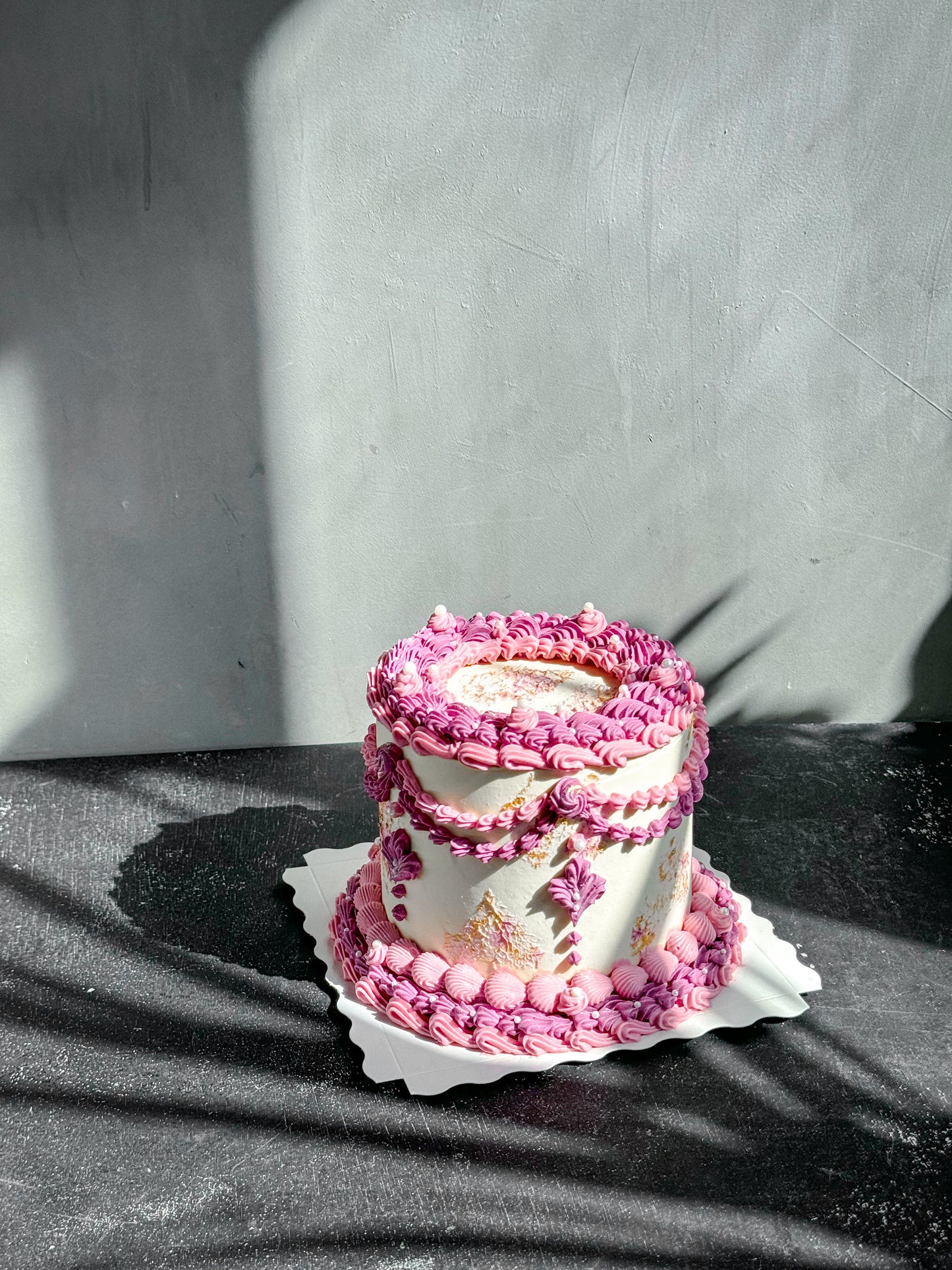 Slice of vintage cake from Kaki Desserts featuring layered frosting and decorative toppings on a white plate.
