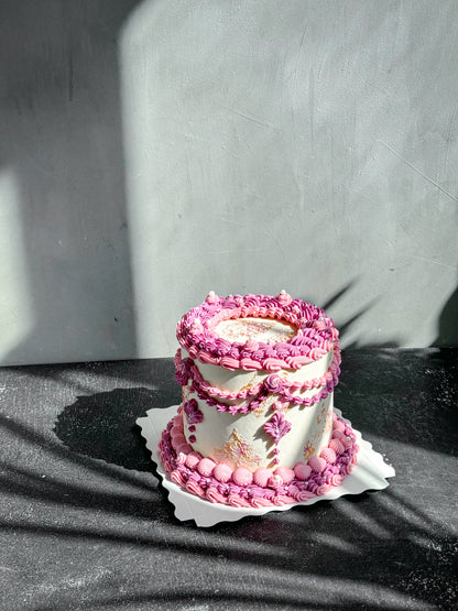 Slice of vintage cake from Kaki Desserts featuring layered frosting and decorative toppings on a white plate.