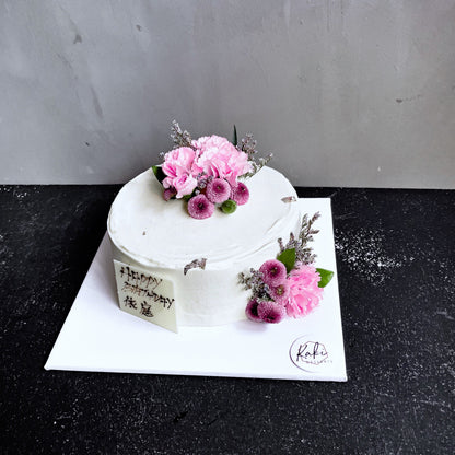 Decorative bespoke cake from Kaki Desserts featuring intricate icing designs and colorful floral accents.