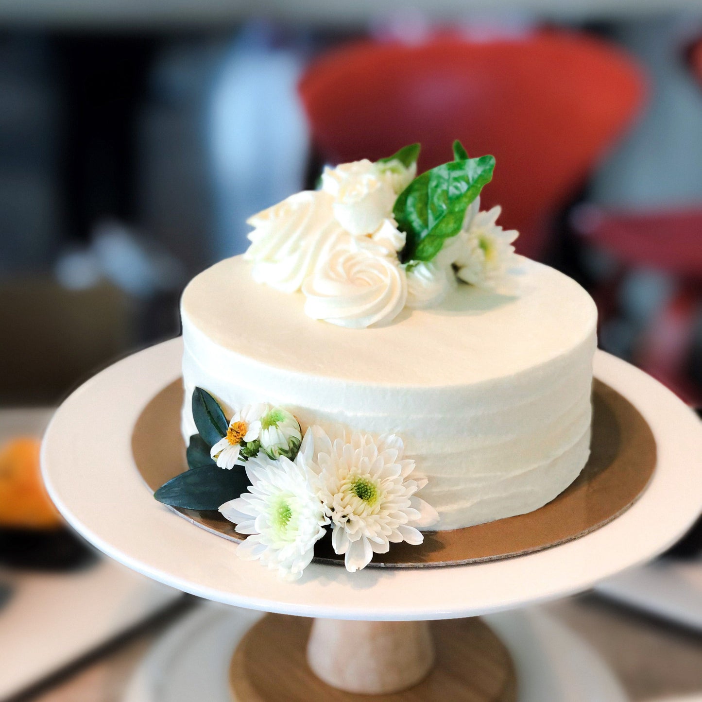 Decorative bespoke cake from Kaki Desserts featuring intricate icing designs and colorful floral accents.