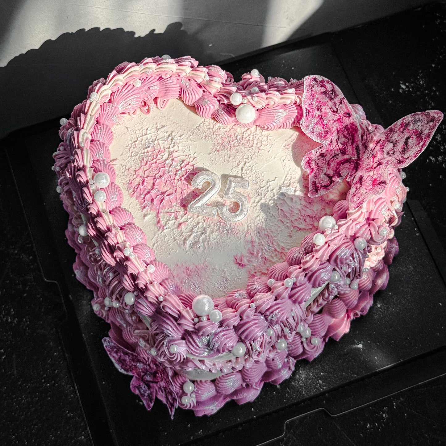 Decorative bespoke cake from Kaki Desserts with intricate icing details and colorful floral accents.