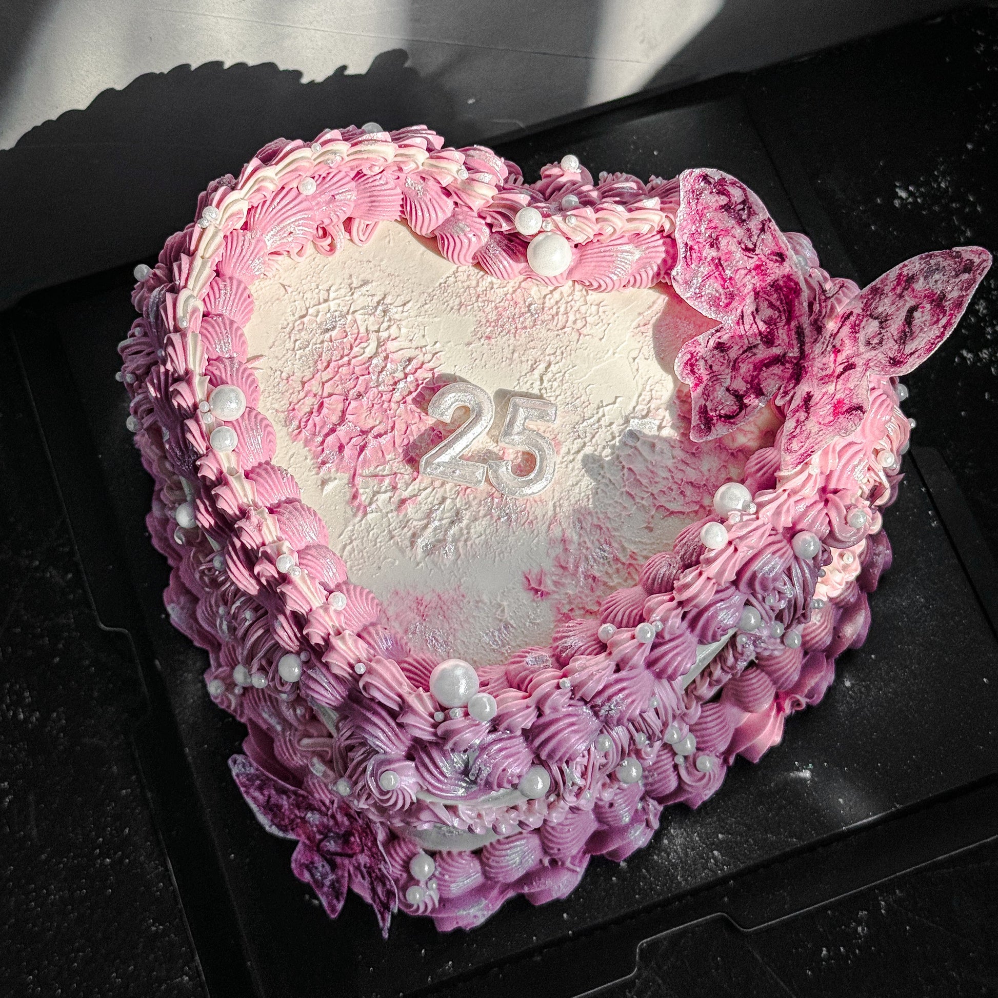 Decorative bespoke cake from Kaki Desserts with intricate icing details and colorful floral accents.