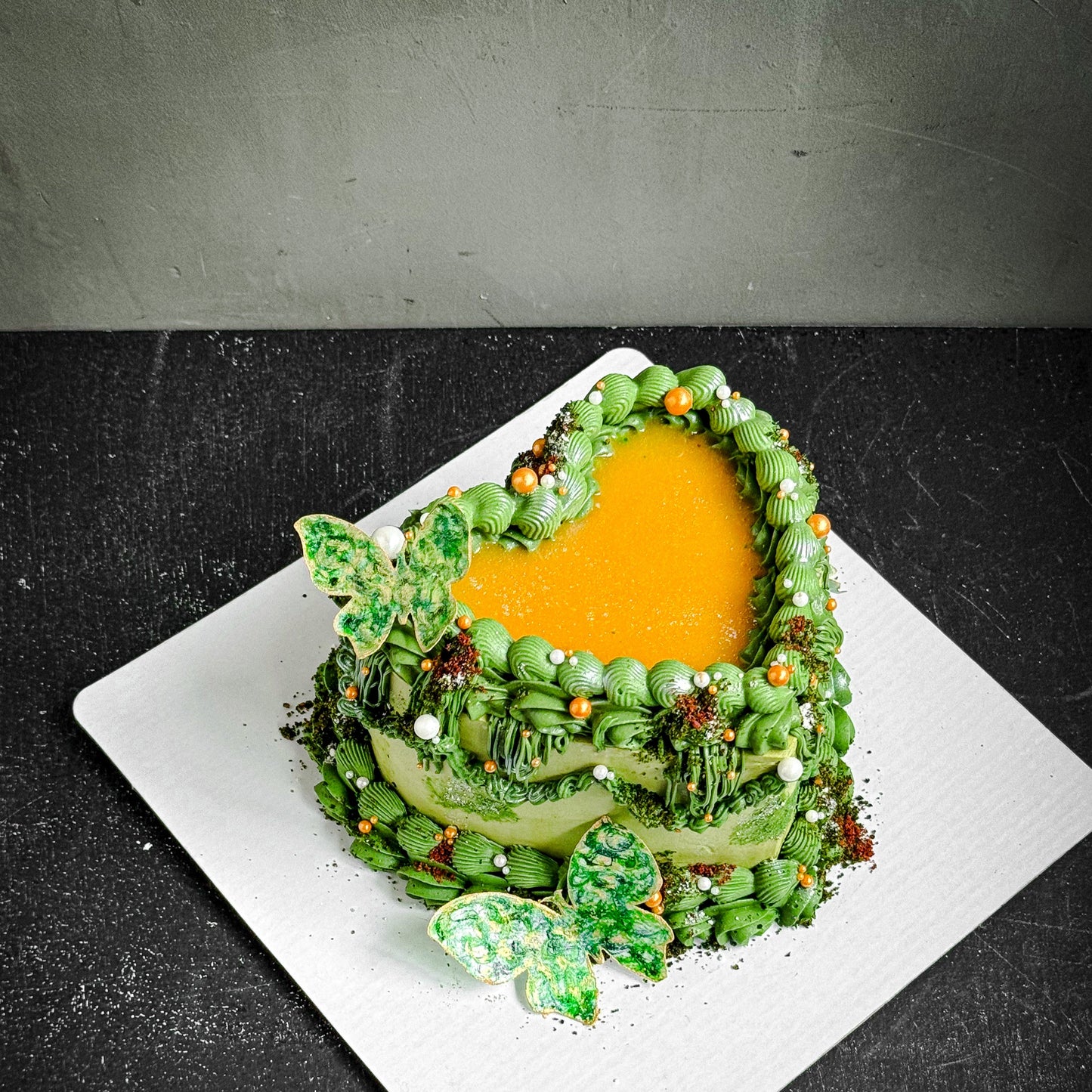 Assorted bespoke cakes from Kaki Desserts with elegant frosting and decorative toppings on a white platter.