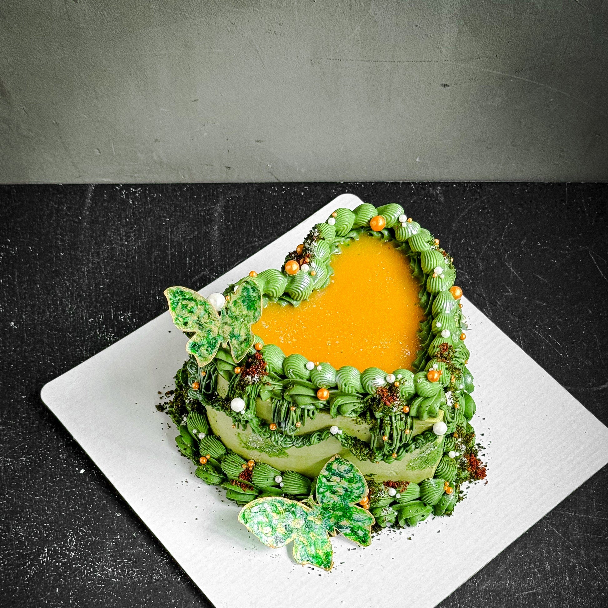 Assorted bespoke cakes from Kaki Desserts with elegant frosting and decorative toppings on a white platter.