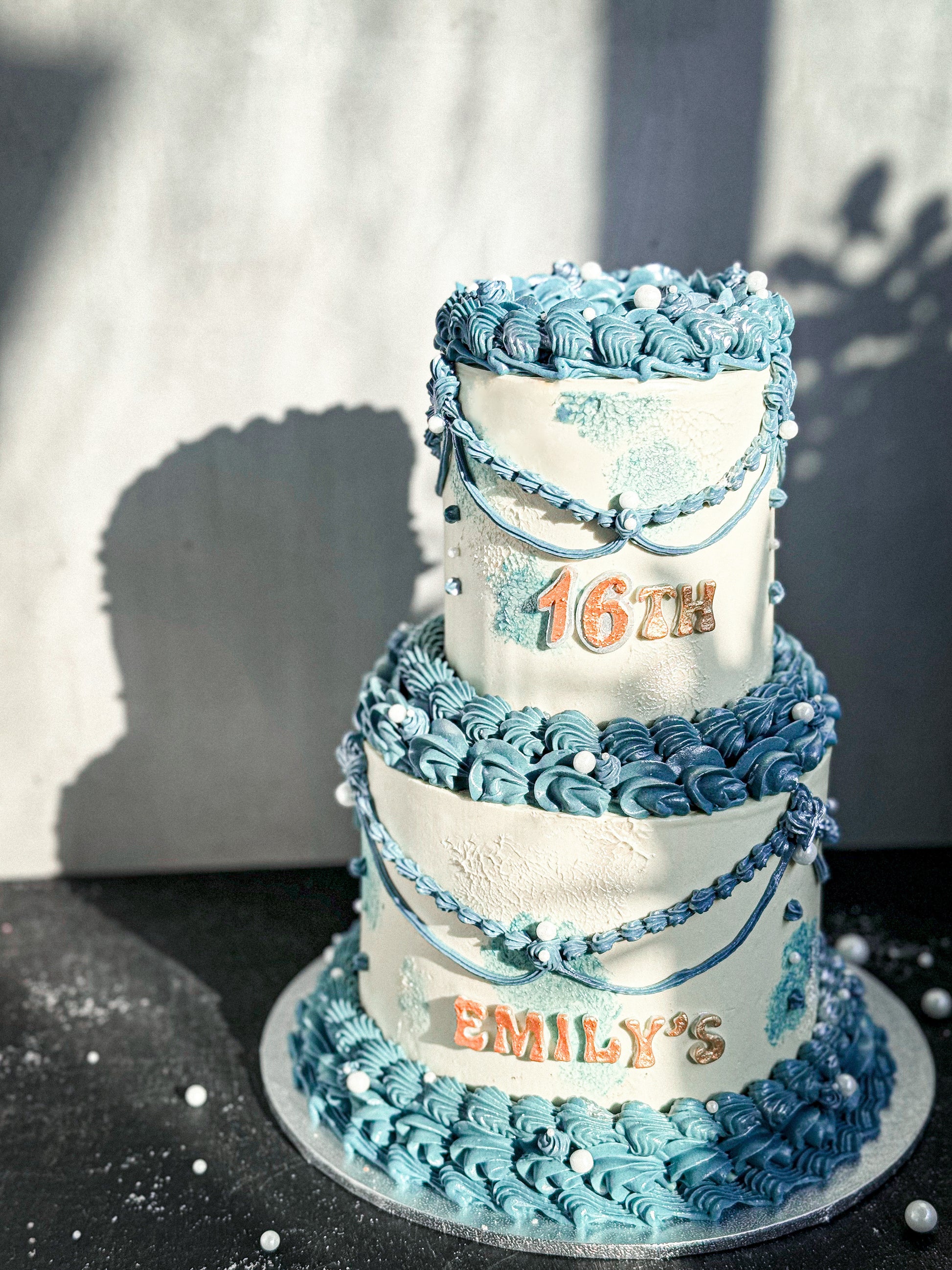 Vintage cake from Kaki Desserts with layered frosting and decorative toppings on a white plate.
