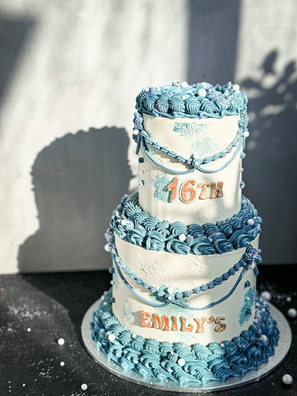 Vintage cake from Kaki Desserts with layered frosting and decorative toppings on a white plate.