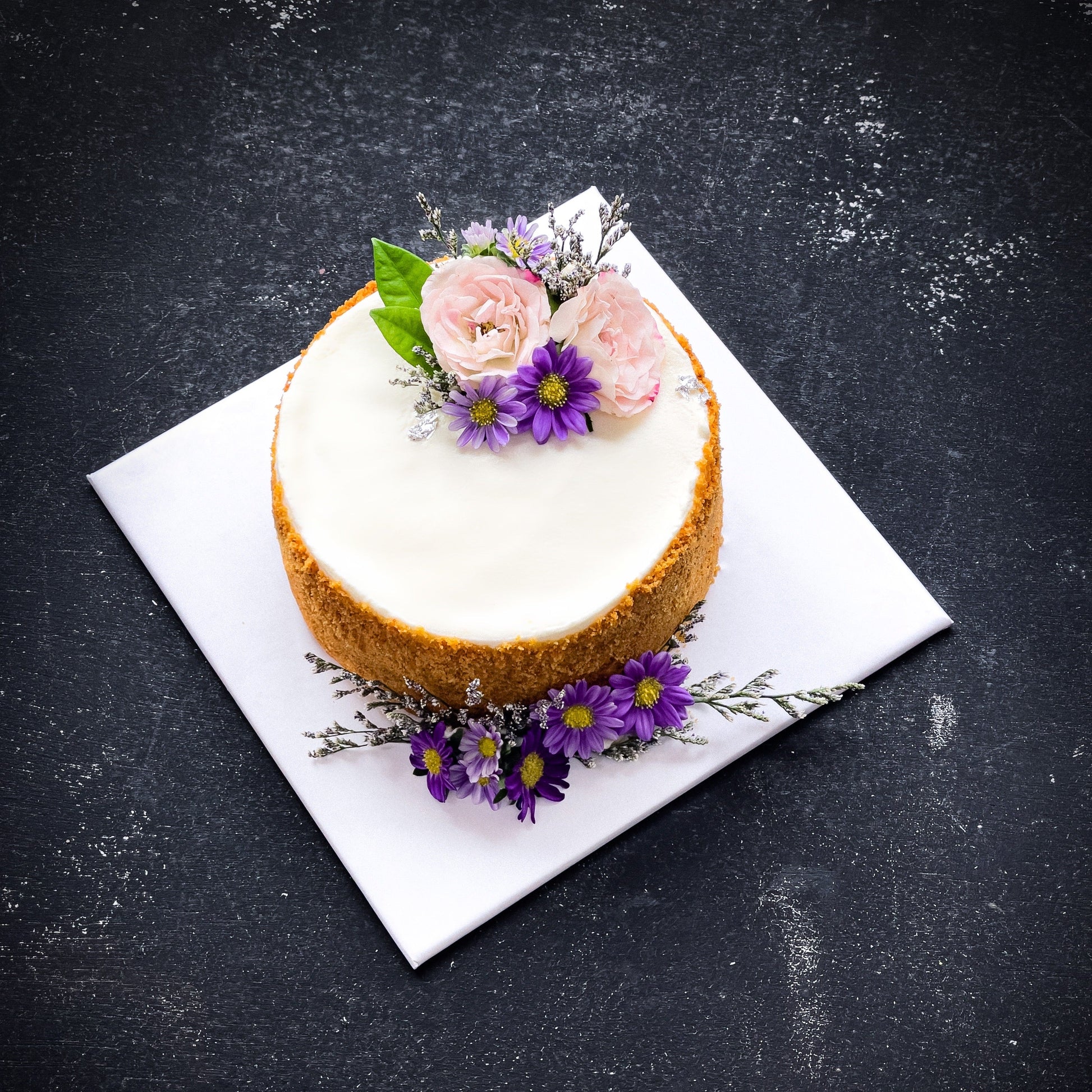 Decorative bespoke cake from Kaki Desserts with intricate frosting details and colorful floral accents.