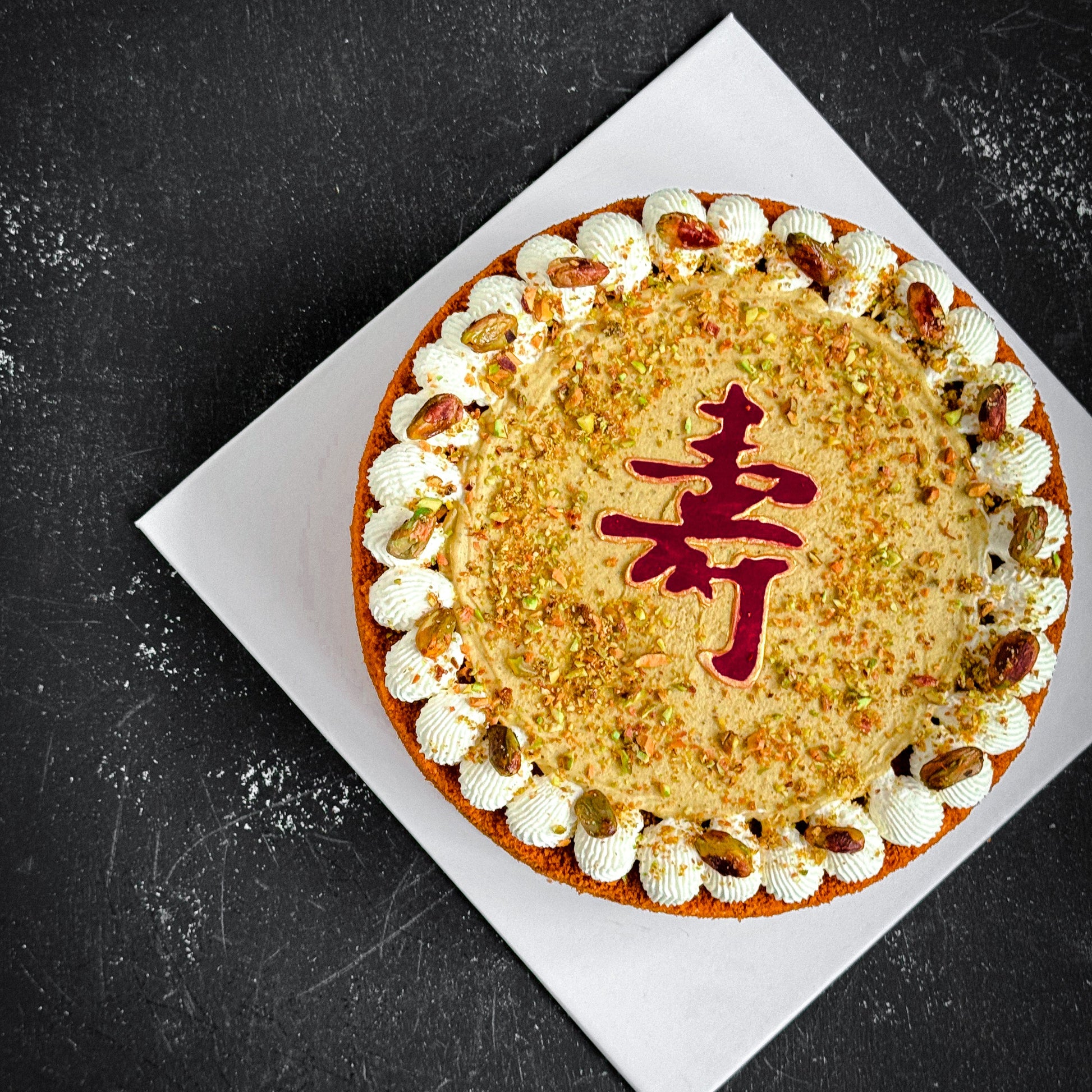 Decorative bespoke cake from Kaki Desserts with intricate floral and geometric icing designs on a white cake base.