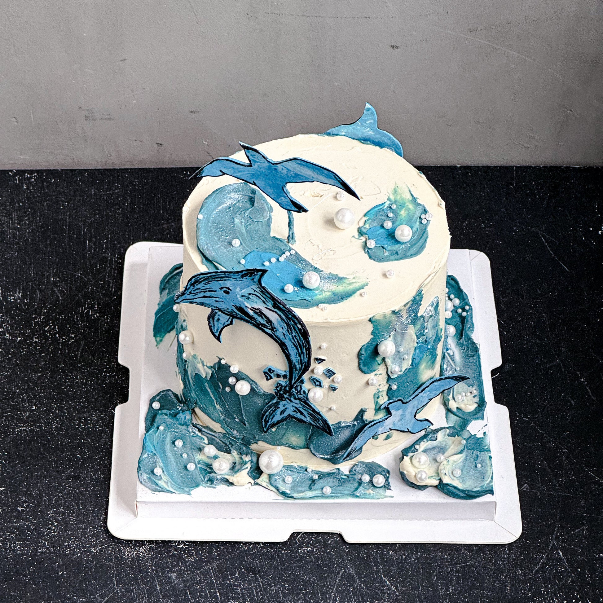 Colorful bespoke cakes from Kaki Desserts with intricate designs and vibrant frosting, displayed on a white cake stand.