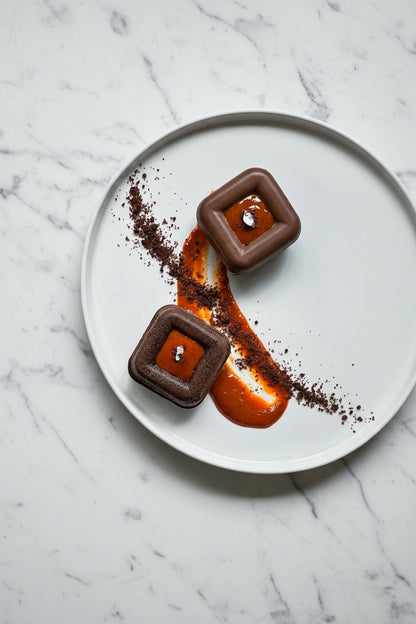 Kaki Desserts bespoke chocolate square cakes displayed on a marble surface, showcasing rich, glossy chocolate frosting.