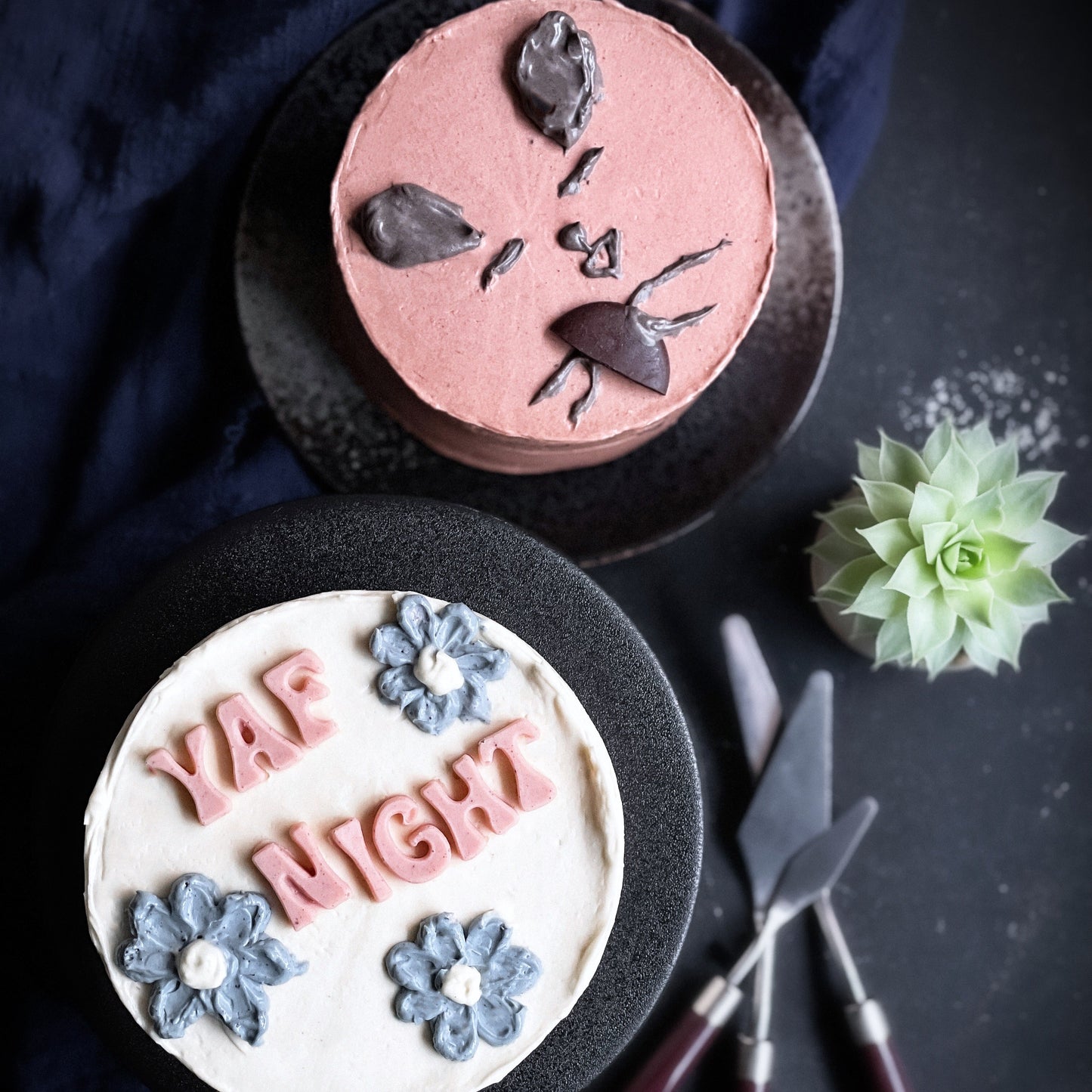 Decorative bespoke cake from Kaki Desserts with elegant frosting and intricate detailing on a white cake stand.