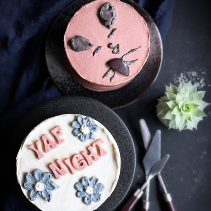 Decorative bespoke cake from Kaki Desserts with elegant frosting and intricate detailing on a white cake stand.