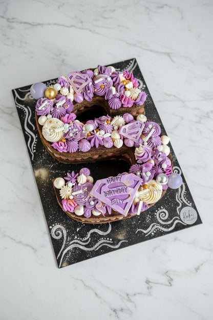 Letter cake from Kaki Desserts featuring colorful, decorated cake slices with letter-shaped designs on a white background.