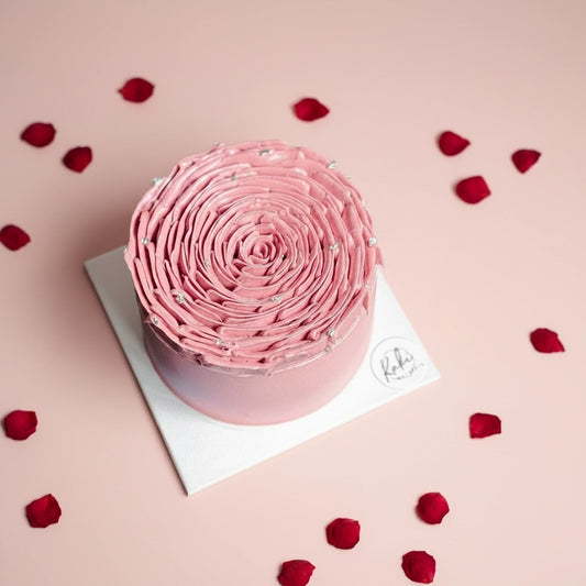 Pink velvet cake topped with red rose petals, showcasing a luxurious and elegant dessert from Kaki Desserts.