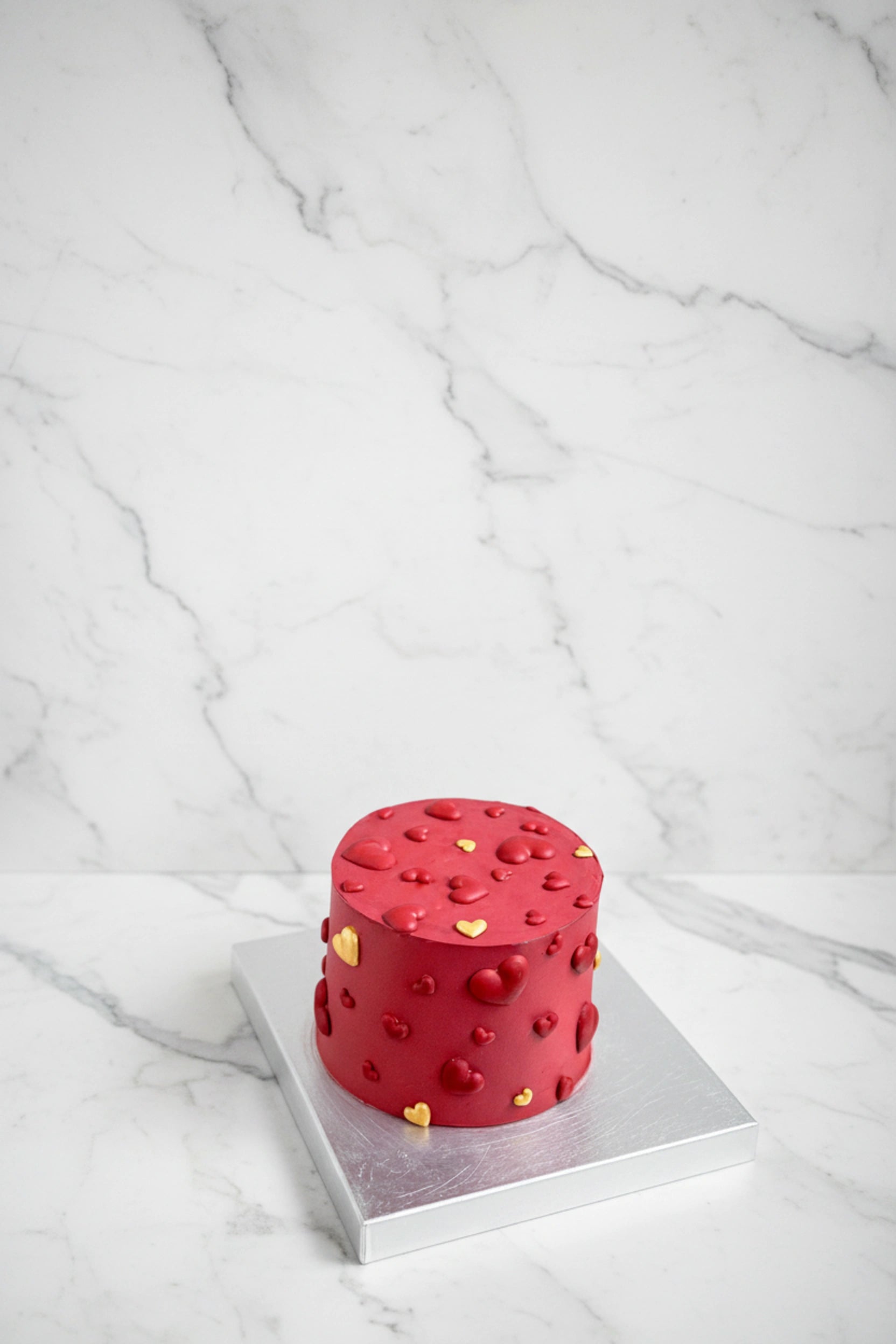 Marble red heart-shaped cake by Kaki Desserts featuring smooth red marbled frosting and elegant design.