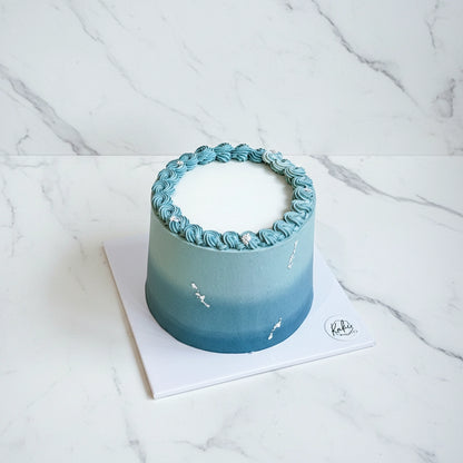 Teal blue ombre marble cake by Kaki Desserts featuring smooth, elegant frosting and a sophisticated design.