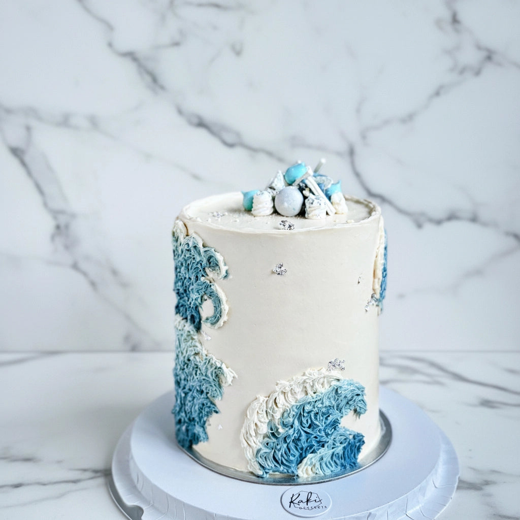 Teal ocean wave marble cake by Kaki Desserts with smooth, marbled teal and white icing resembling ocean waves.