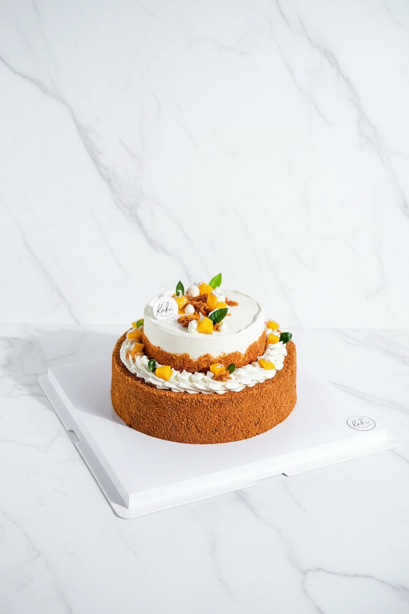 Two-tier mango float cake by Kaki Desserts, featuring layers of fresh mango and creamy dessert in a polished presentation.